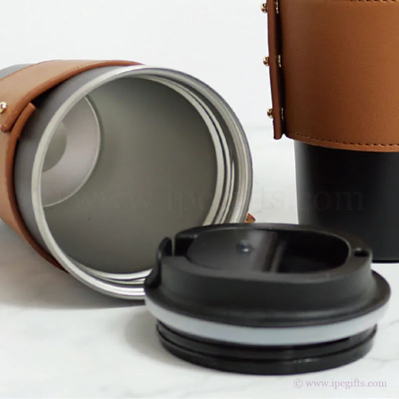 Close-up of a travel mug with a brown leather sleeve and black lid on a white background.