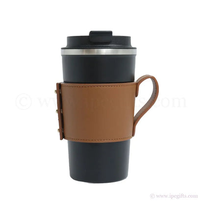 Black travel mug with a thick brown leather sleeve on a white background