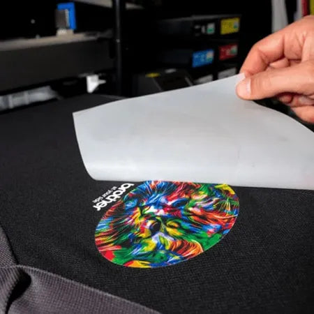 Colorful heat transfer design being applied to a black surface with a brand logo.